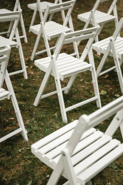 Çimlerin üzerinde duran düğün sandalyeleri. Beyaz
