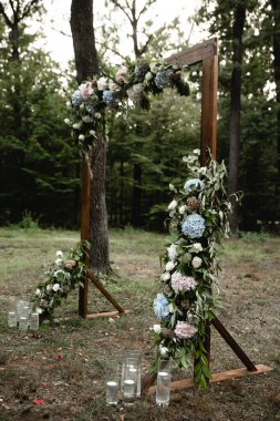 Çiçek açan düğün kemeri, güller, ortanca ve okaliptüs. Düğün ahşabı süslemesi. Çiçeklerle, yeşillikle ve salon alanıyla süslenmiş ahşap tahta. Düğün fotoğrafı bölgesi. Parti alanı kırsal tarzı.