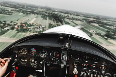 Pilot kabininden görüntü. Kontrol paneli. Tarlaların ve köyün üzerinde uçak uçuran bir pilota yaklaş. Gösterge panelinde çok sayıda düğme, navigasyon aygıtı