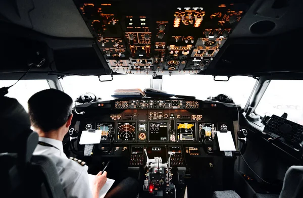 View from pilot\'s cabin. Control panel. Close up of a pilot flying airplane over the fields and village. Many buttons, navigation devices on dashboar