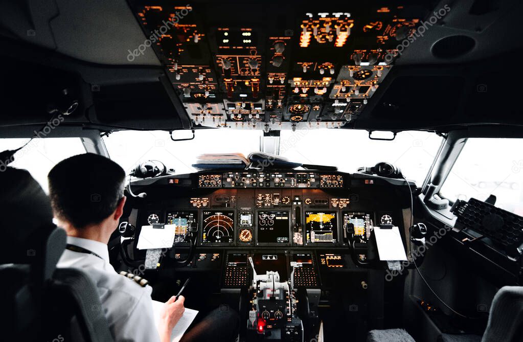 View from pilot's cabin. Control panel. Close up of a pilot flying airplane over the fields and village. Many buttons, navigation devices on dashboar