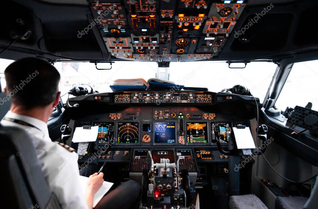 View from pilot's cabin. Control panel. Close up of a pilot flying airplane over the fields and village. Many buttons, navigation devices on dashboar