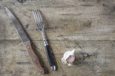 Çatal, bıçak ve sarımsak tepesinde eski ahşap kurulu