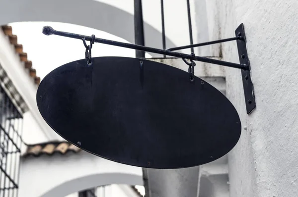 Blank black metal sign on a shop wall