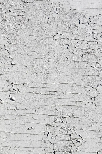 Texture of few layers of cracked, peeling off old white paint
