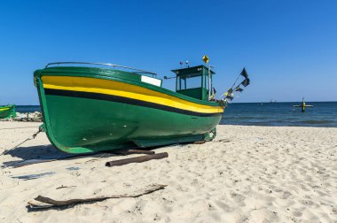 Küçük, yeşil balıkçı teknesi kıyıda dinleniyor. Gdynia, Polonya yakınlarındaki plaj
