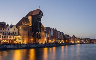 Gün batımında Motlawa Nehri kıyısında Gdansk Eski şehir. Binalar arasında ünlü ortaçağ vinç
