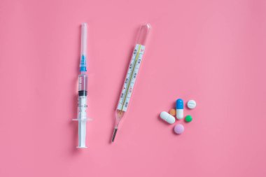 Mercury termometre ve şırınga ve bir pembe hapları.