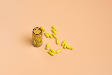 Cam şişe turuncu zemin üzerine sarı hap. Metin için yer kopyalayın