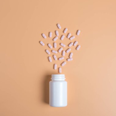 Pembe hap, tablet ve turuncu zemin üzerine beyaz şişe. Metin için yer kopyalayın