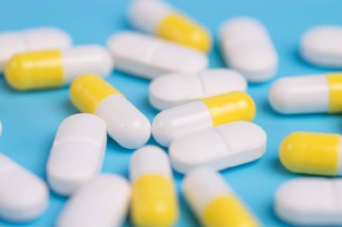 Sarı ve beyaz hap veya kapsül kopya alanı ile mavi bir arka plan üzerinde.