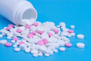 Beyaz ve pembe hap, tablet ve mavi zemin üzerine beyaz şişe. Metin için yer kopyalayın