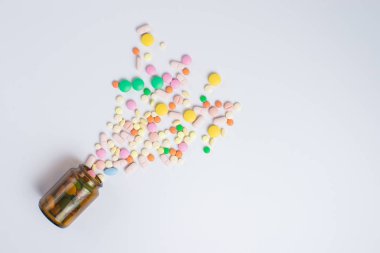 İlaç hapları, beyaz arka planda cam şişedeki haplar.