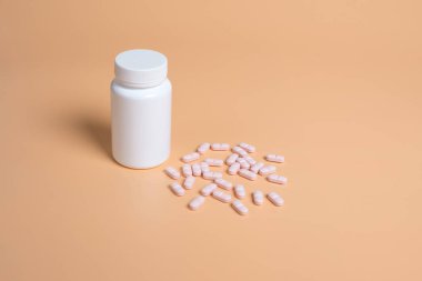 Pembe hap, tablet ve turuncu zemin üzerine beyaz şişe. Metin için yer kopyalayın