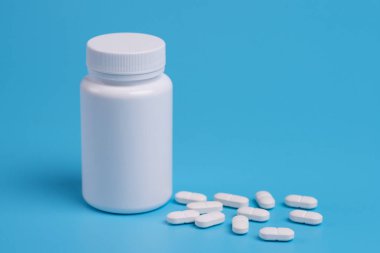 Beyaz hap, tablet ve mavi zemin üzerine beyaz şişe. Metin için yer kopyalayın