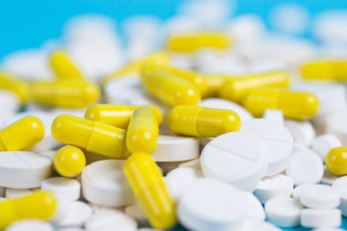 Sarı ve beyaz hap veya kapsül kopya alanı ile mavi bir arka plan üzerinde.