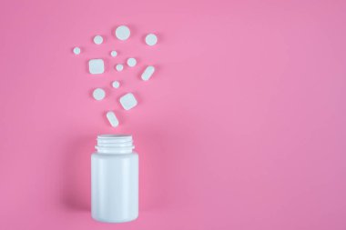 Beyaz hap, tablet ve pembe bir arka plan üzerinde beyaz şişe. Metin için yer kopyalayın