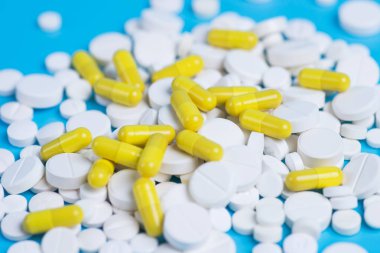 Sarı ve beyaz hap veya kapsül kopya alanı ile mavi bir arka plan üzerinde.