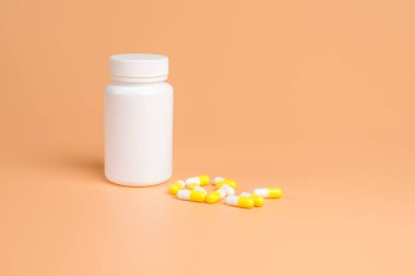 Sarı ve beyaz hap, Tablet ve turuncu zemin üzerine beyaz şişe. Metin için yer kopyalayın