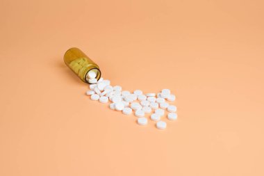 Kahverengi cam şişe portakal bir arka plan üzerinde beyaz hap. Metin için yer kopyalayın