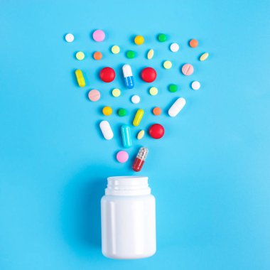 Renkli hap, Tablet ve mavi zemin üzerine beyaz şişe