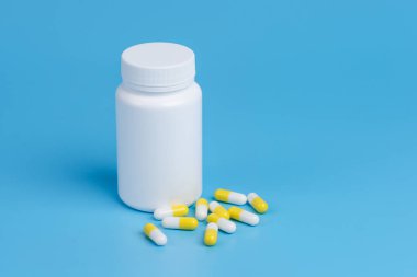 Beyaz ve sarı hap, Tablet ve beyaz şişe mavi backgro üzerinde