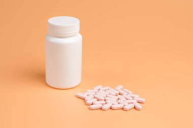 Pembe hap, Tablet ve turuncu zemin üzerine beyaz şişe