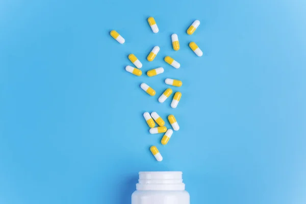 Medicamento píldoras o comprimidos blancos y amarillos caen del blanco — Foto de Stock