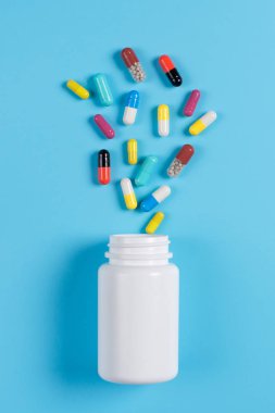 Renkli hap, Tablet ve mavi zemin üzerine beyaz şişe
