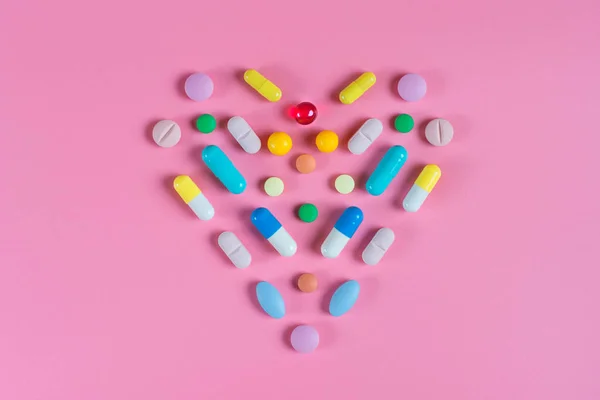 El corazón se compone de tabletas sobre un fondo rosa — Foto de Stock
