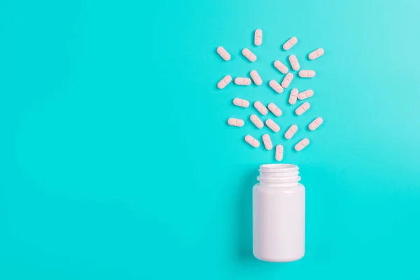 Rosa piller, tabletter och vit flaska på blå bakgrund — Stockfoto
