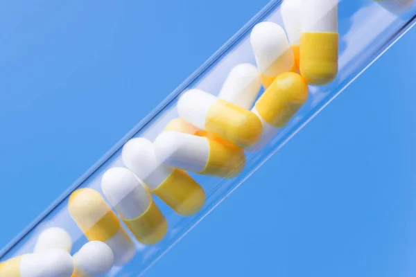 Tıp sarı ve beyaz hap mavi backgro test tüp — Stok fotoğraf