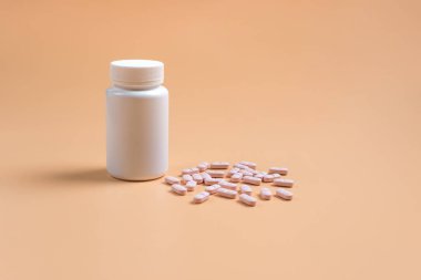 Pembe hap, Tablet ve turuncu zemin üzerine beyaz şişe