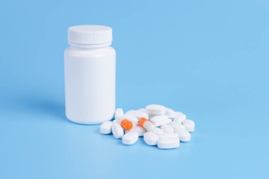 Beyaz ve turuncu hap, Tablet ve beyaz şişe mavi backgro üzerinde
