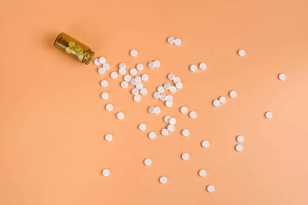 Pastillas blancas en la botella de vidrio marrón sobre un fondo naranja — Foto de Stock