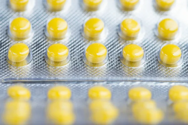 Medicine yellow pills packed in blisters. Macro. Copy space for