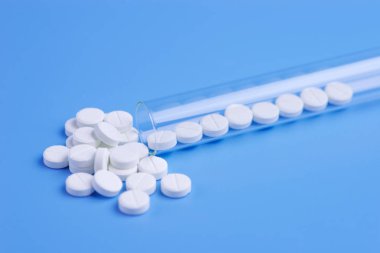 Tıp beyaz hap mavi arka plan üzerinde test tüpü içinde. Kopya s