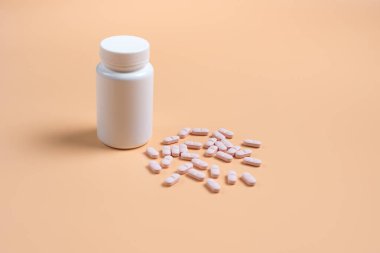 Pembe hap, Tablet ve turuncu zemin üzerine beyaz şişe