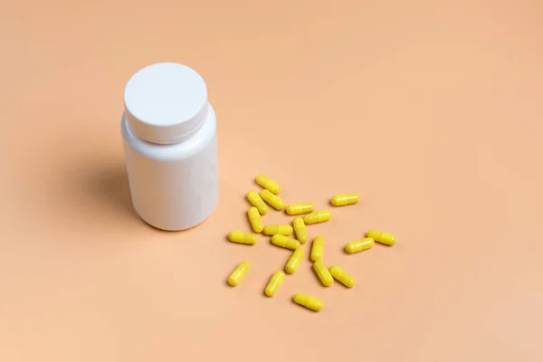 Žluté prášky, tablety a bílá láhev na pozadí — Stock fotografie