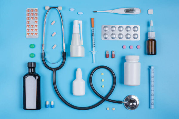 Stethoscope and pills in blisters on a blue background.