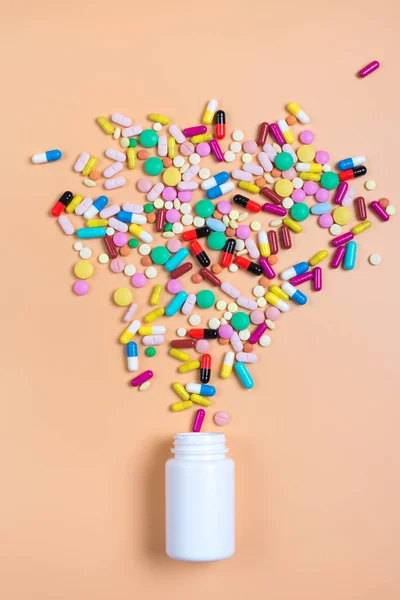 Píldoras de color, tabletas y frasco blanco sobre fondo de orenge — Foto de Stock