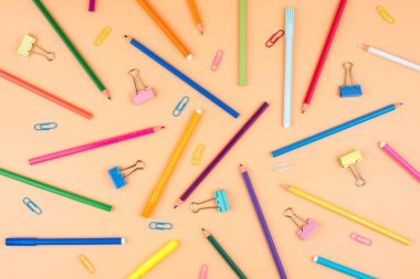 Turuncu bir arka plan üzerinde renkli okul malzemeleri. 