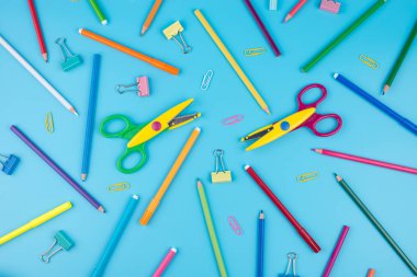 Renkli okul malzemeleri ve notepadon mavi bir arka plan. 
