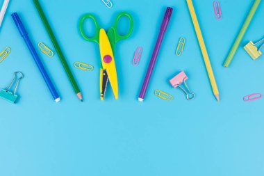 Renkli okul malzemeleri ve notepadon mavi bir arka plan. 