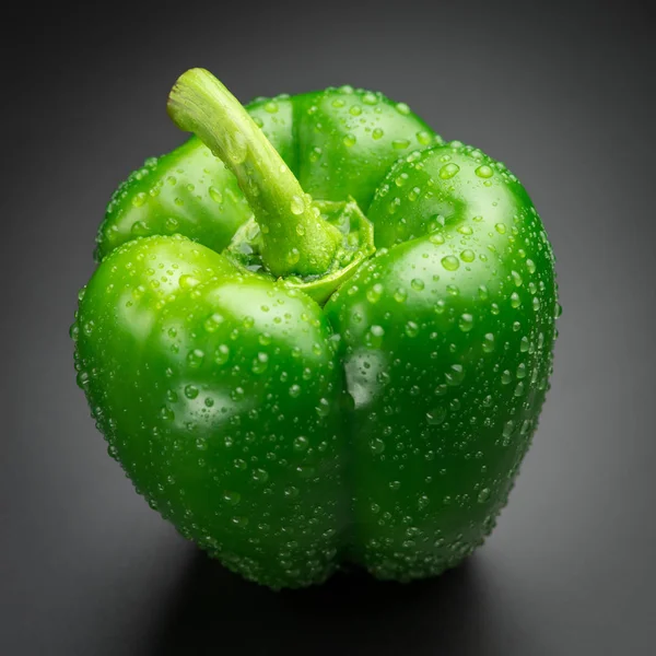 Green pepper with water drops on a black background. — Stock Photo, Image