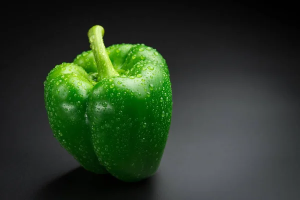 Pimenta verde fresca com gotas de água em um fundo preto — Fotografia de Stock