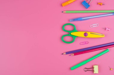Pembe arka plan üzerine bir ödev üzerine renkli okul malzemeleri.