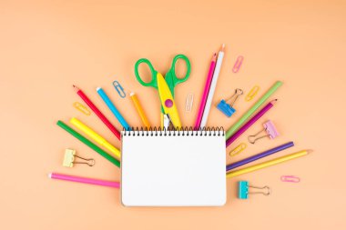 Turuncu arka plan üzerine renkli okul malzemeleri. 