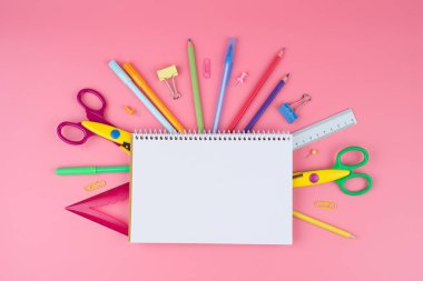 Pembe arka plan üzerine bir ödev üzerine renkli okul malzemeleri.