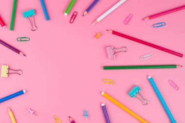 Pembe arka plan üzerine bir kağıt üzerinde renkli okul malzemeleri